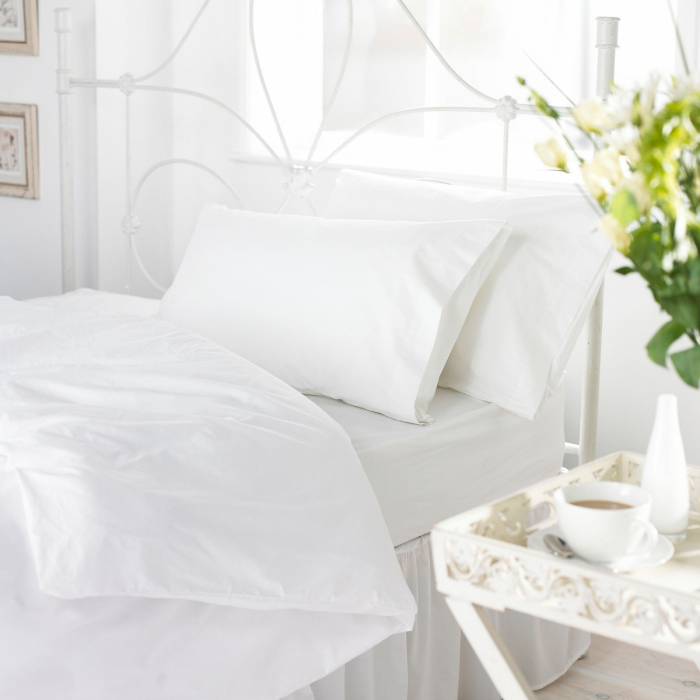 White 144 thread count 50/50 polycotton duvet cover on bed with pillows in white bedroom.
