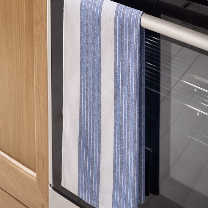 Multi-stripe blue tea towel made from 100% cotton hanging off an oven door